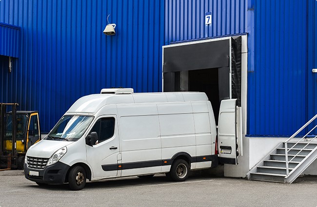 White van loading at a warehouse door.